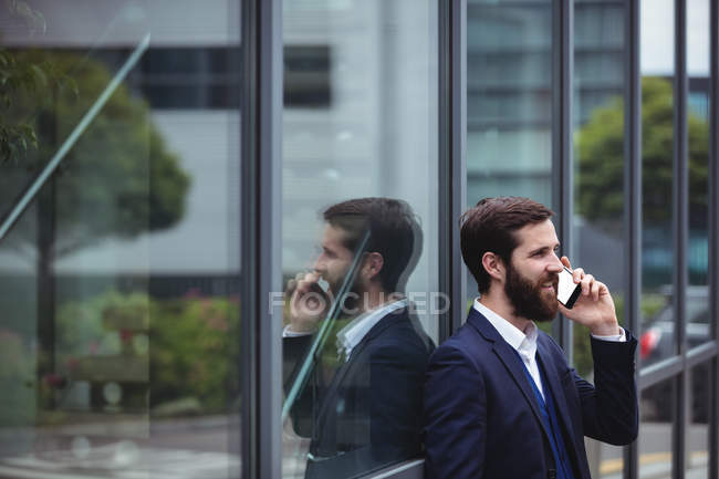 Empresario hablando por teléfono móvil fuera de la oficina - foto de stock