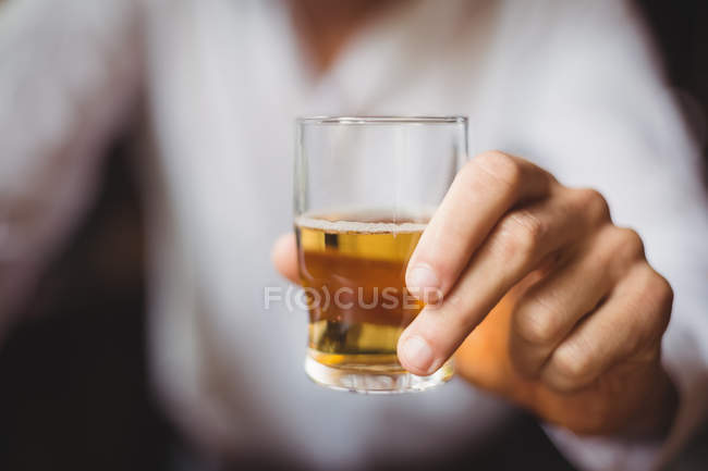 Gros plan du barman tenant un verre de whisky au comptoir du bar — Photo de stock