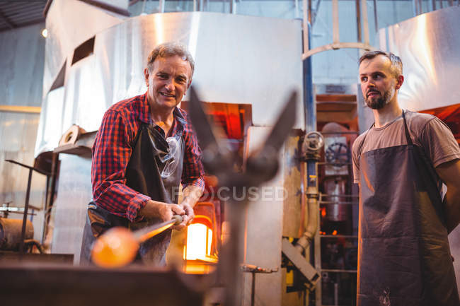 Glassblowers shaping a molten glass at glassblowing factory — Stock Photo