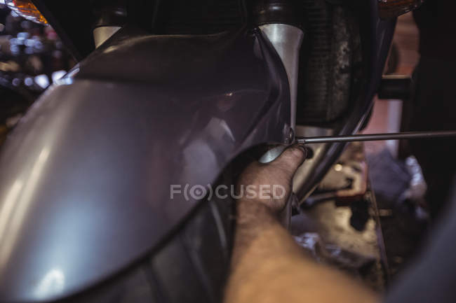 Primer plano del mecánico examinando moto en el taller - foto de stock