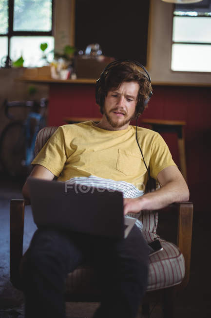 Mechaniker hört Musik, während er in der Werkstatt am Laptop arbeitet — Stockfoto
