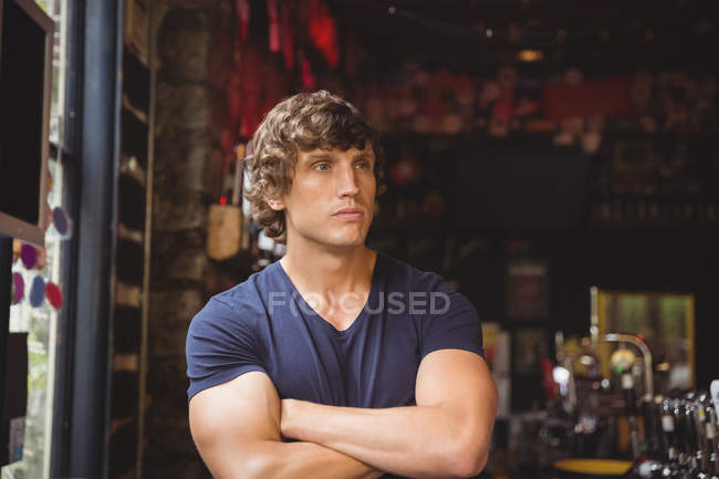 Bar tender standing with arms crossed at bar counter — Stock Photo