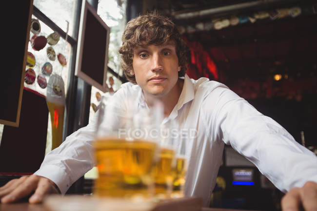Bartender looking at glasses of beer in bar — Stock Photo