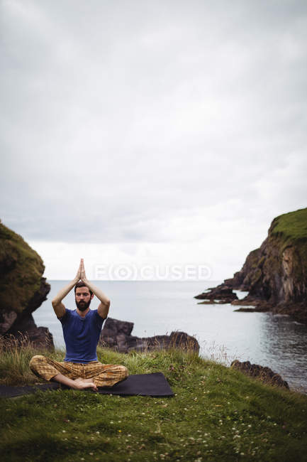 Man performing yoga on cliff — Stock Photo