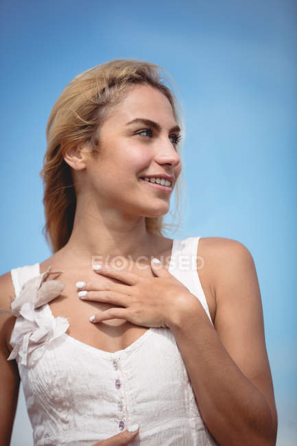 Porträt einer lächelnden Frau, die vor blauem Himmel wegschaut — Stockfoto