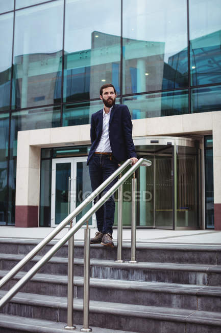 Удумливий бізнесмен стоїть біля входу в офісну будівлю — стокове фото