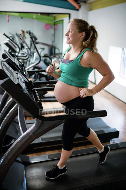 Pregnant woman exercising on treadmill at gym — Stock Photo