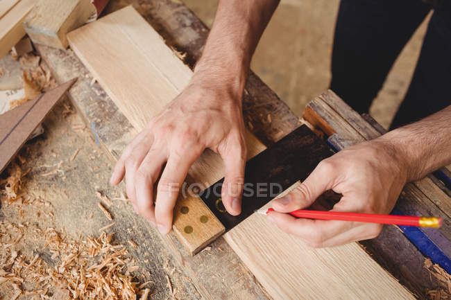 Manos de hombre trabajando sobre una tabla de madera en el astillero - foto de stock