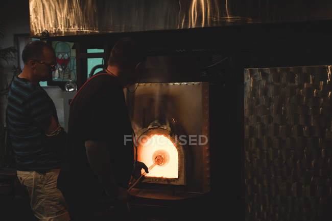 Team of glassblowers heating glass in furnace at glassblowing factory — Stock Photo