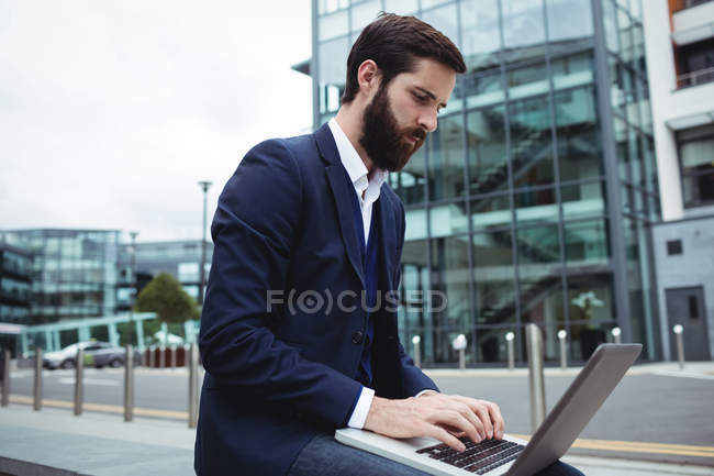 Homme d'affaires attentif utilisant un ordinateur portable à l'extérieur du bureau — Photo de stock