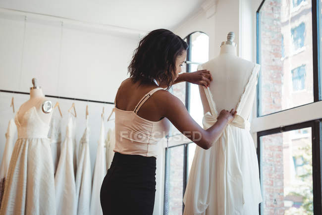 Créatrice de mode féminine ajustant la robe sur un mannequin en studio — Photo de stock
