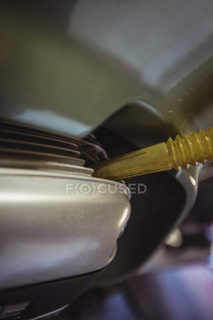 Close-up de óleo a ser reabastecido em tanque de óleo de moto na oficina — Fotografia de Stock