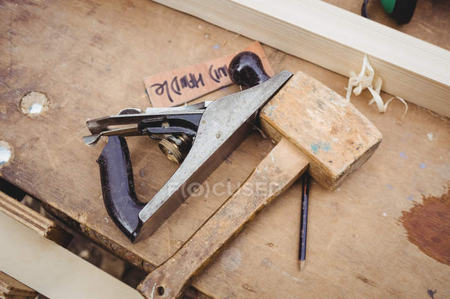 Hand plane and hammer on wooden plank in boatyard — Stock Photo