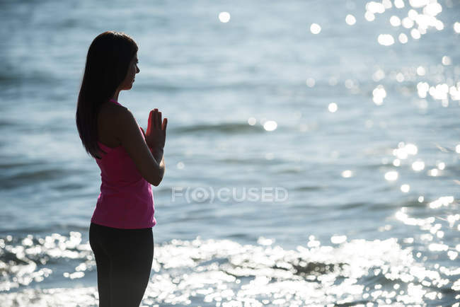 Silhouette of woman meditating on beach on sunny day — Stock Photo