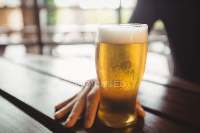 Homem com copo de cerveja na mesa no bar — Fotografia de Stock