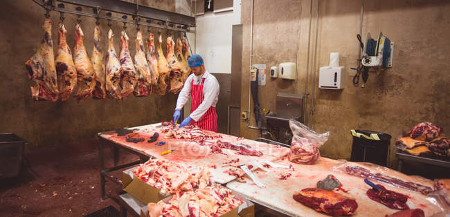 Açougueiro corta carne na arrecadação do talho — Fotografia de Stock
