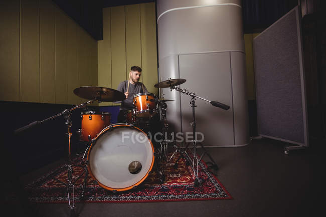 Studente maschio che suona il tamburo in uno studio — Foto stock