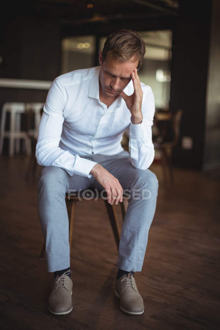 Homem de negócios tenso sentado na cadeira no escritório — Fotografia de Stock
