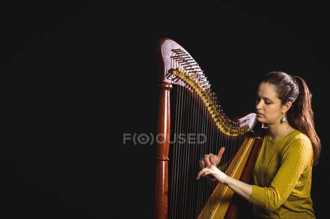 Внимательная женщина, играющая на арфе в музыкальной школе — стоковое фото