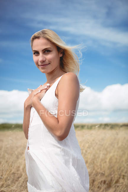 Porträt einer schönen blonden Frau, die auf dem Feld steht und in die Kamera schaut — Stockfoto