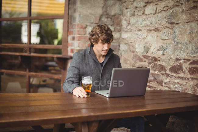 Средняя часть человека с помощью ноутбука в баре — стоковое фото