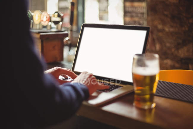 Man using laptop at bar counter — Stock Photo