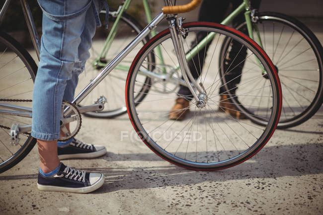 Donna in piedi con bicicletta su strada — Foto stock