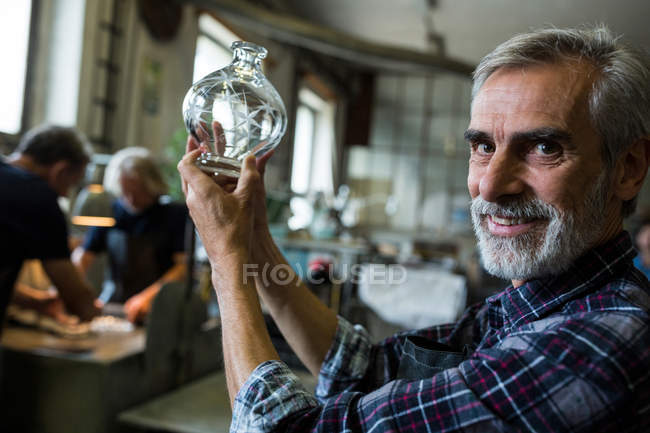 Retrato de soplador de vidrio mirando cristalería en fábrica de soplado de vidrio - foto de stock