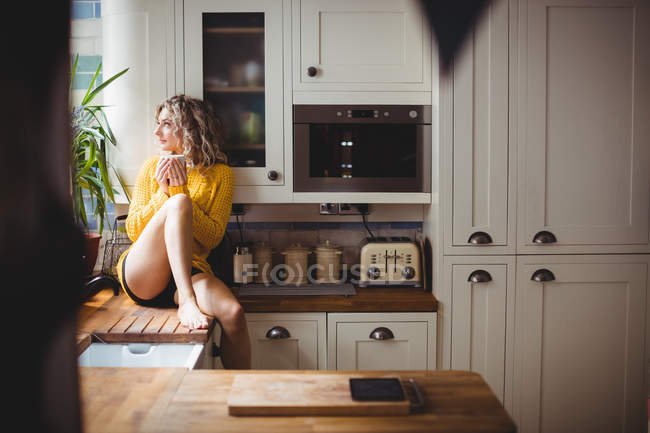 Mulher bonita tomando café na cozinha em casa — Fotografia de Stock
