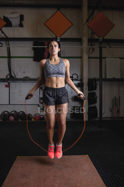 Woman exercising with skipping rope in fitness studio — Stock Photo