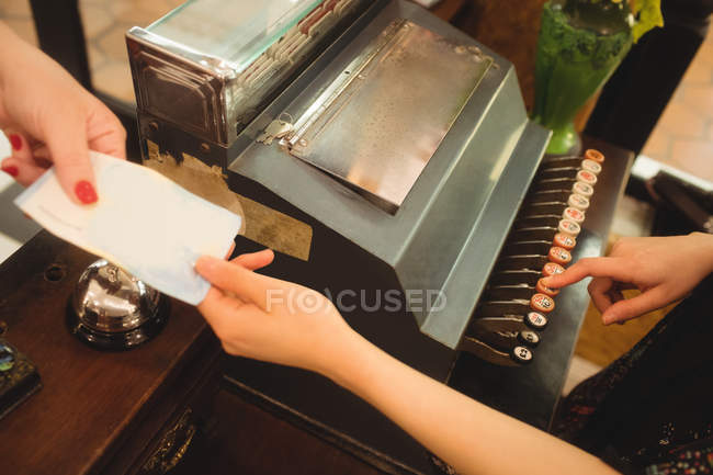 Caissière acceptant un paiement au comptoir en magasin — Photo de stock