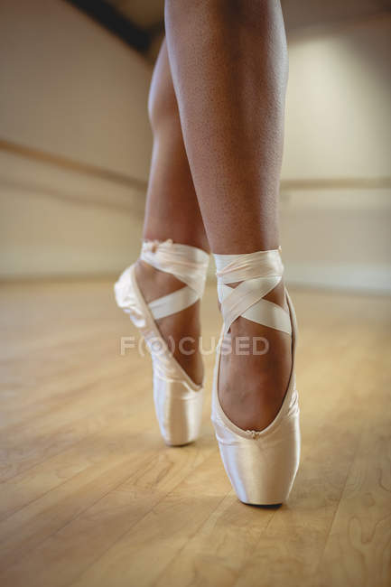 Low section of Ballerina standing on tiptoe in pointe shoes — Stock Photo