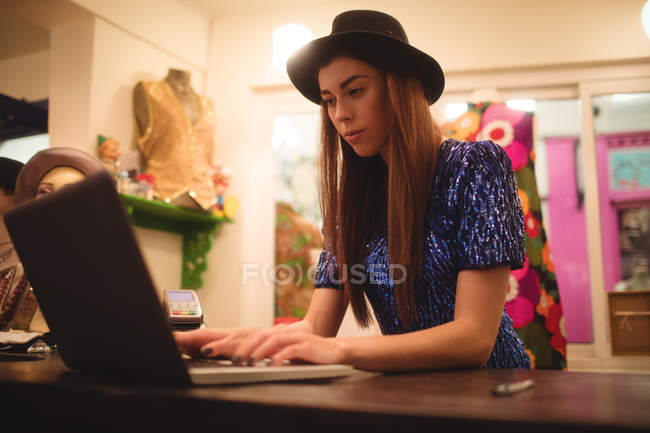 Personnel féminin utilisant un ordinateur portable à un comptoir dans un magasin de boutique — Photo de stock