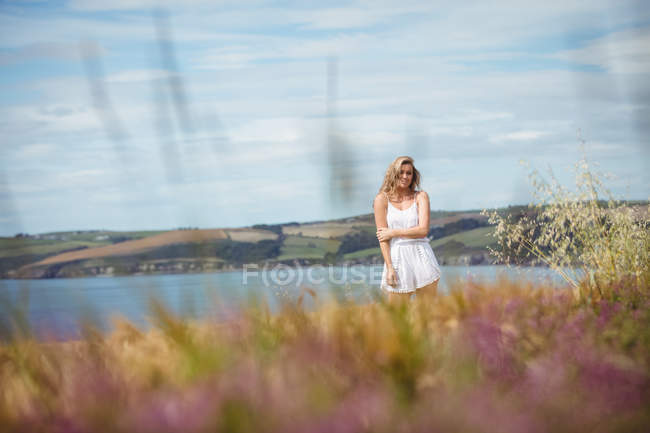 Femme debout dans le champ de blé par une journée ensoleillée dans la campagne — Photo de stock