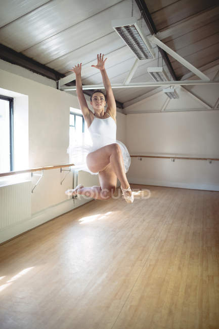 Балерина занимается балетным танцем и прыгает в студии — стоковое фото