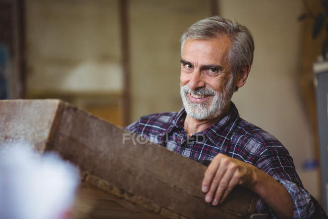 Portrait of glassblower holding a wooden crate in glassblowing factory — Stock Photo