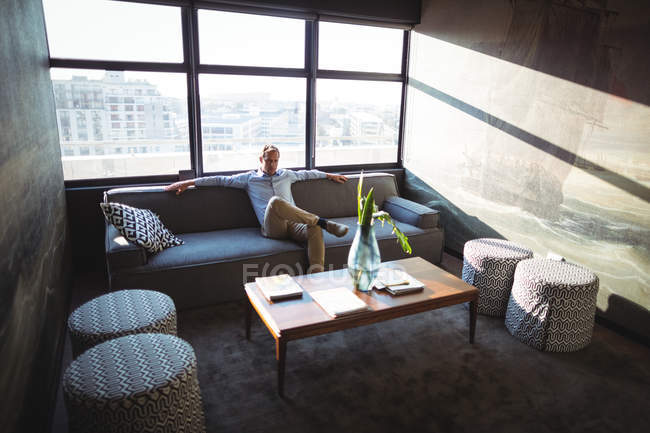 Безтурботний бізнесмен сидить на дивані в офісі — стокове фото