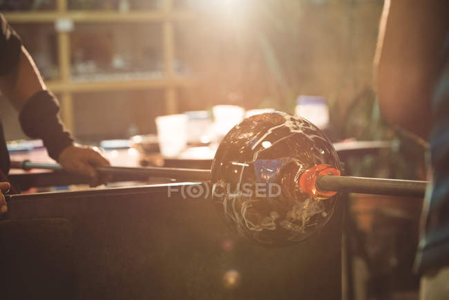 Команда стеклодувов, формирующих стекло на трубе на стекольном заводе — стоковое фото