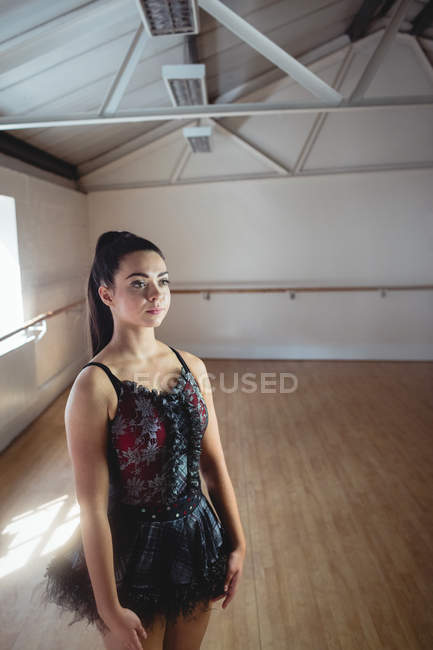Балерина стоит в балетной студии и смотрит в сторону — стоковое фото