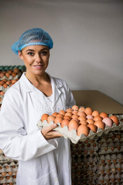 Portrait du personnel féminin tenant un plateau d'œufs dans une usine — Photo de stock