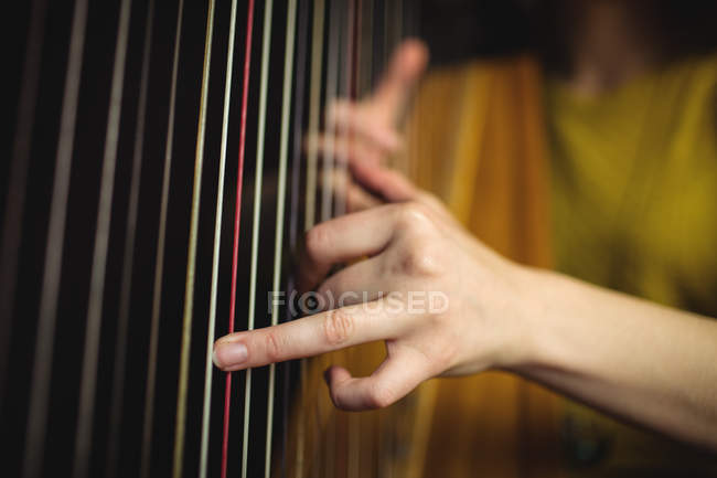 Sección media de la mujer tocando un arpa en la escuela de música - foto de stock