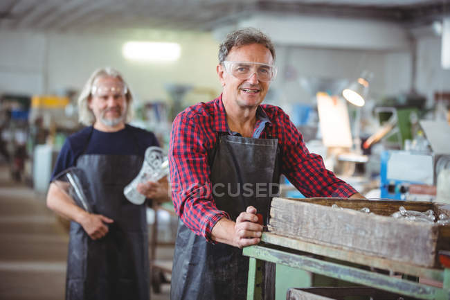Portrait of glassblowers holding wooden container at glassblowing factory — Stock Photo