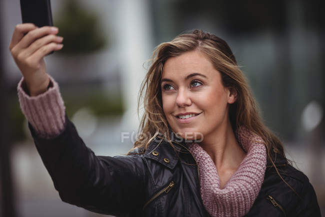 Belle femme souriante prenant selfie sur smartphone à la rue — Photo de stock