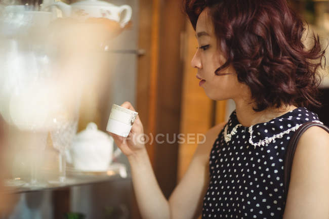 Mulher elegante selecionando uma xícara em lojas de antiguidades — Fotografia de Stock
