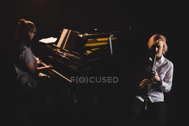 Duas alunas tocando clarinete e piano em um estúdio — Fotografia de Stock