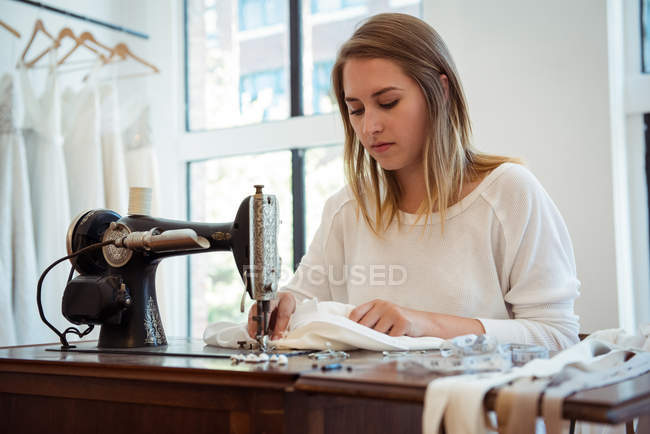 Costureira feminina costura na máquina de costura no estúdio — Fotografia de Stock