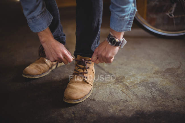 Mechanic tying shoe lace in bicycle workshop — Stock Photo