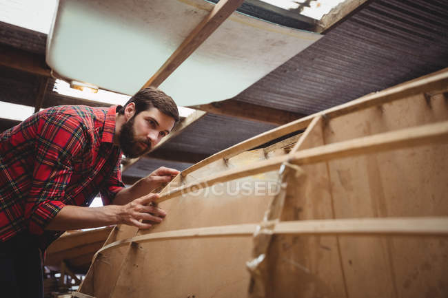 Homem preparando moldura de barco de madeira no estaleiro — Fotografia de Stock