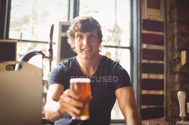 Portrait of man holding glass of beer at bar — Stock Photo