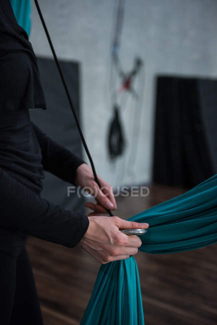 Female gymnast holding fabric rope in fitness studio — Stock Photo